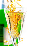 A glass of sparkling wine on the background of the bottle with a festive tinsel.