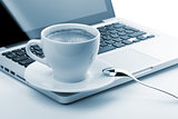 Cappuccino cup on laptop. Toned