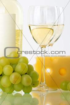 Bottle of white wine, wine glasses, grape and cheese