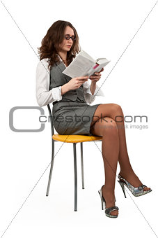 girl is sitting on a chair and reading a book 