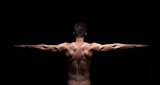 Muscular man with arms streched out on black background