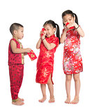Asian children peeking into red packet 