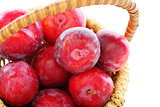 Ripe red plums in a basket close up.