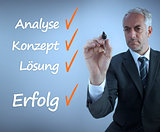 Attractive businessman writing a success checklist in german