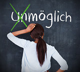 Attractive woman looking at a chalkboard with success in german on it