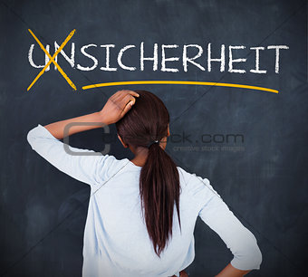 Woman looking at a chalkboard with sicherheit on it