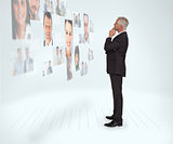 Thoughtful businessman looking at a wall covered by profile pictures