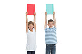 Happy brother and sister holding their notebooks above their head