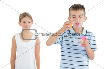 Boy making bubbles while his sister looking at him