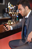 Handsome businessman sending a text while having a drink