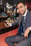 Cheerful businessman sending a text while having a drink