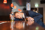 Unmoving businessman holding whiskey glass lying on a counter