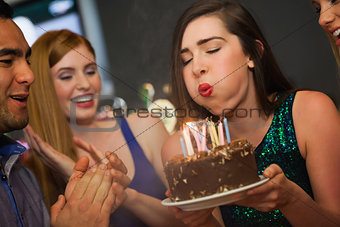 Attractive woman blowing the candles on her birthday cake