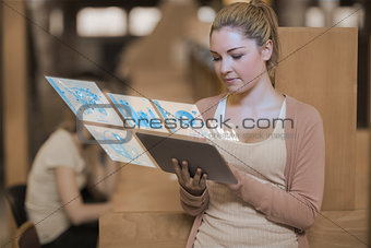 Pretty blonde student working on her futuristic tablet
