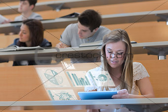 Pretty blonde student in university working on her futuristic tablet