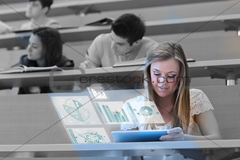 Pretty blonde student analysing graphs on her futuristic tablet
