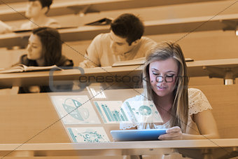 Pretty blonde student analysing graphs on her digital tablet