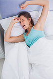 Well rested brunette woman stretching and yawning in bed