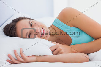 Woman lying in bed with eyes open and smiling
