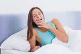 Sleepy woman yawning in bed