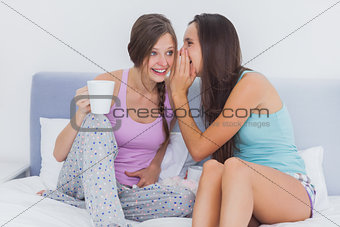 Friends sitting in bed gossiping