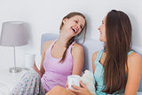 Pretty friends chatting over coffee in bed