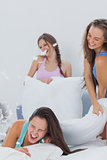 Laughing friends having pillow fight in bed