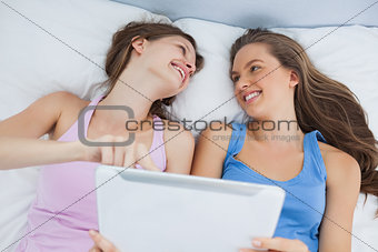 Friends lying in bed with tablet