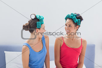 Girls wearing hair rollers sitting in bed