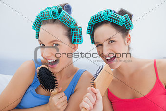 Friends in hair rollers singing into their hairbrushes