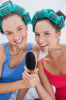 Happy girls in hair rollers holding hairbrush