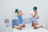 Girls in hair rollers having pillow fight