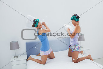 Girls in hair rollers having pillow fight