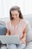 Happy casual woman using laptop on sofa