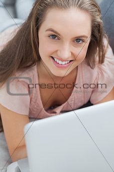 Woman lying on sofa with laptop