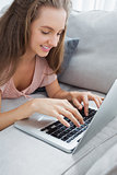 Side view of casual woman using laptop on sofa