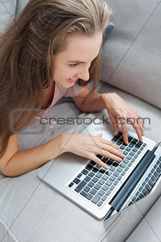 Overhead view of casual woman using laptop on sofa