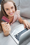 Woman shopping online with her laptop smiling at camera