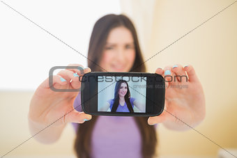 Smiling girl taking a photo of herself with her mobile phone