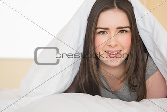 Smiling girl looking at camera lying in her bed