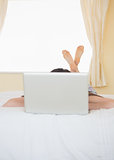 Girl lying on a bed behind a laptop