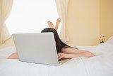 Girl on a bed hiding behind a laptop