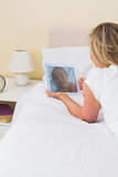 Attentive woman using a tablet pc lying on her bed