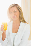 Content woman looking at camera enjoying a glass of orange juice