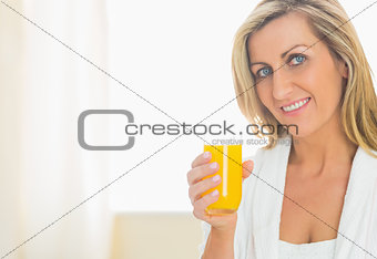 Satisfied woman looking at camera enjoying a glass of orange juice