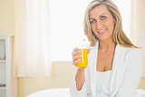 Cheerful woman looking at camera enjoying a glass of orange juice