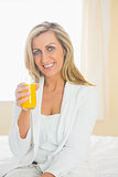Joyful woman looking at camera enjoying a glass of orange juice