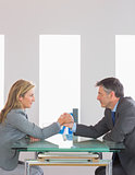 Two content businesspeople having an arm wrestling sitting around a table