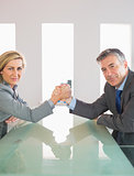 Two smiling businesspeople having a showdown sitting around a table