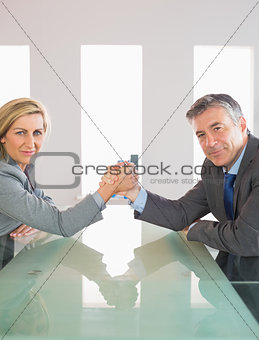 Two smiling businesspeople having a showdown sitting around a table